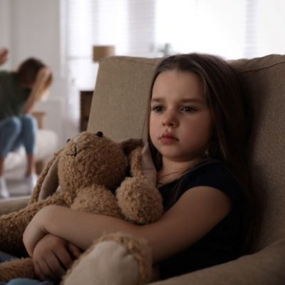 Child holding teddy bear while parents argue in background. Image, Adobe.
